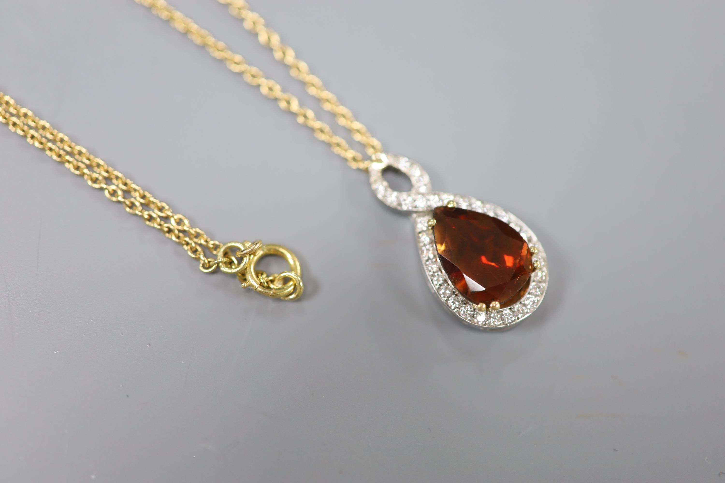 A white and yellow metal, garnet and diamond set teardrop shaped pendant, 29mm, on an 18k fine link chain,